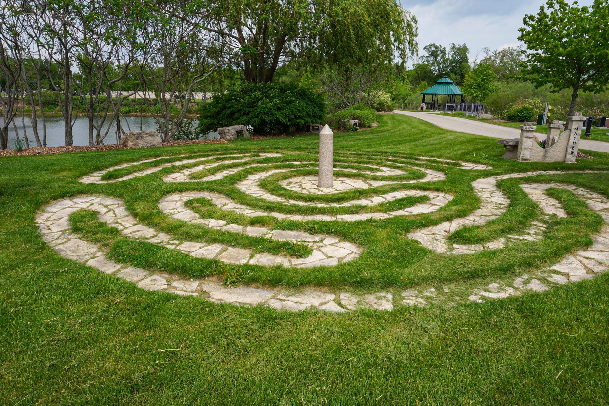 Labyrinth paving among green grass.
