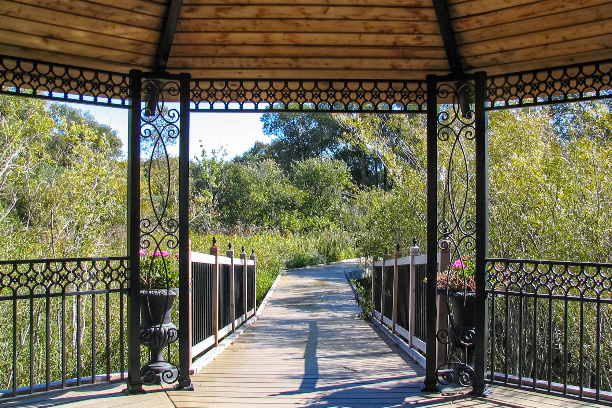 View from inside a gazebo with wooded roof, metal details, and wooden boardwalk