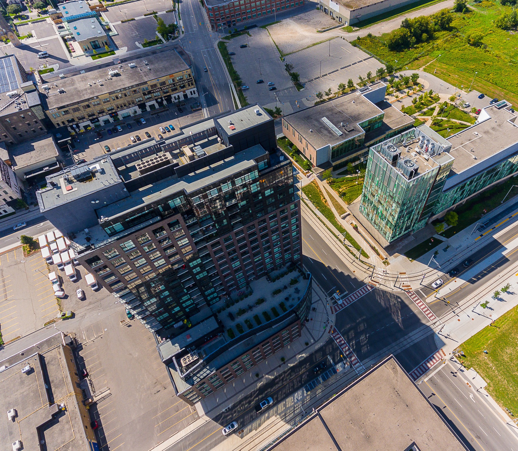Aerial view of One Victoria Condos at the intersection of King Street and Victoria Street with Communitech and University of Waterloo pharmacy building in view. The rooftop amenity for the condo tower is in view.