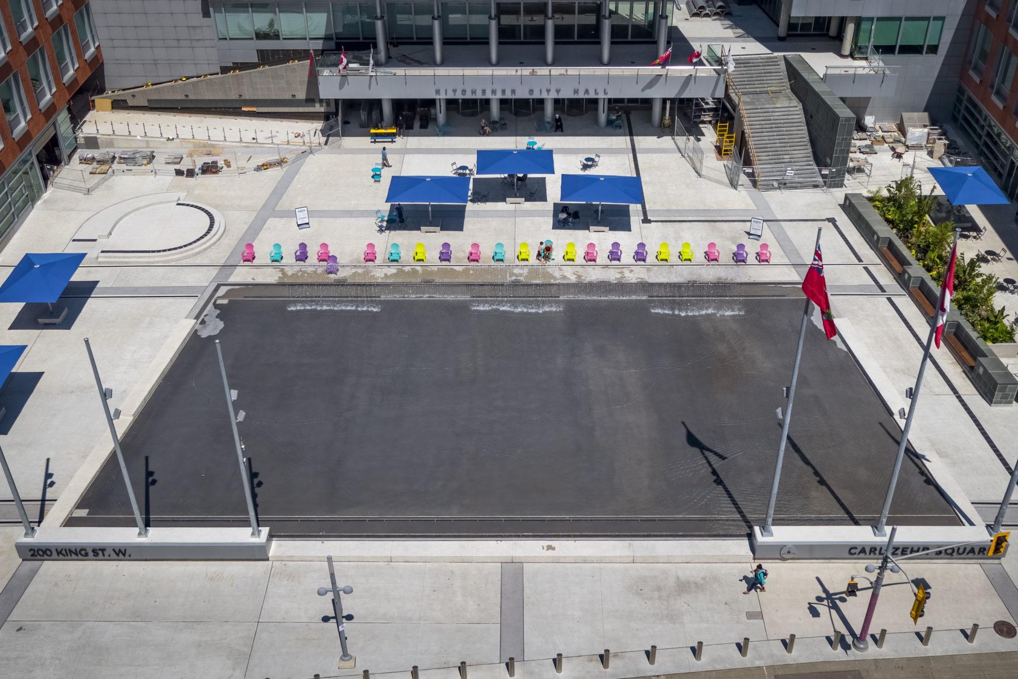 Aerial view of Kitchener City Hall Outdoor spaces with a water feature in the centre that will be a skating rink in the winter months. The rink is surrounded by City Hall buildings.