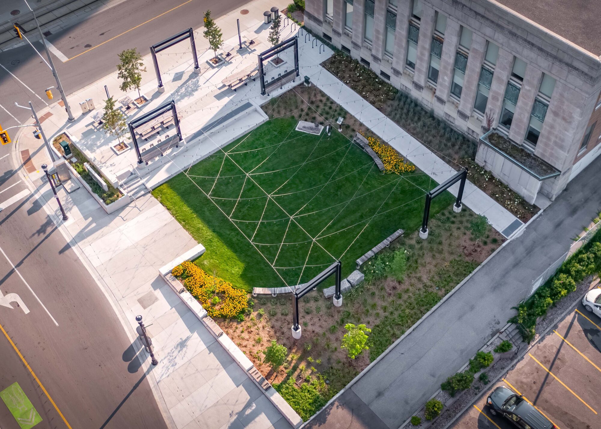 Aerial view of Vogelsang Green, an open green with edge seating, and outdoor sitting areas along Duke Street in downtown Kitchener. Award logos at the bottom of image.